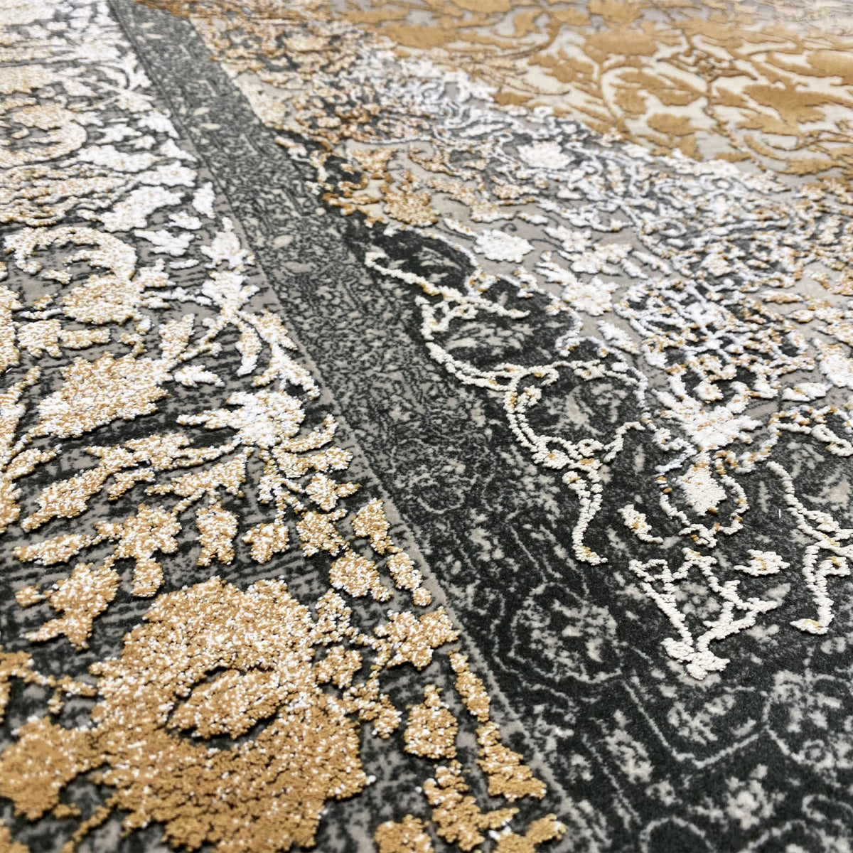 Teppichdetail: kontrastreiches Muster mit Goldakzenten und dunkelgrauen Ornamentlinien.