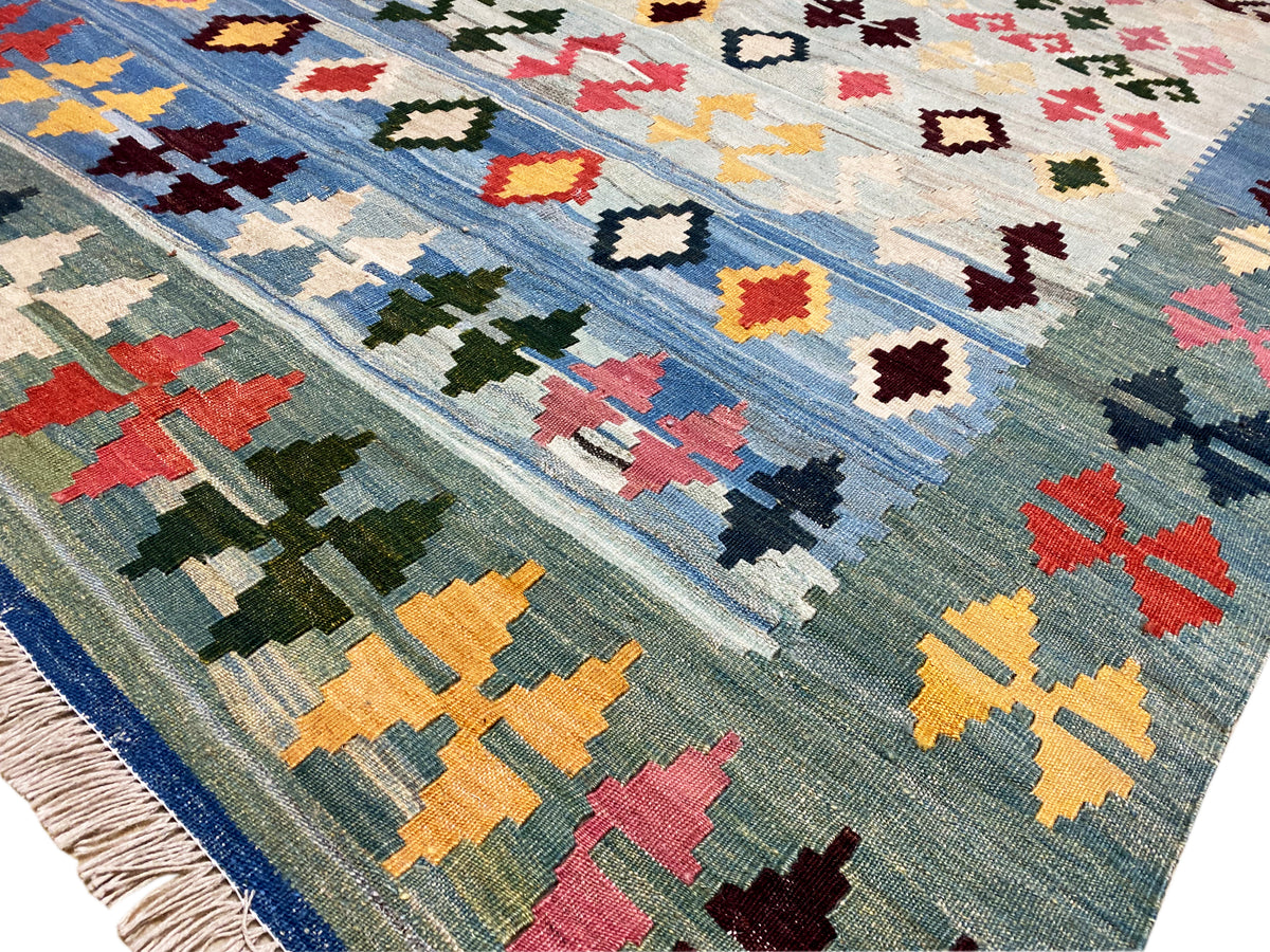 Detailansicht: blauer Kelim mit bunten Kreuz-, Rauten- und Zackenmotiven, gewebte Oberfläche