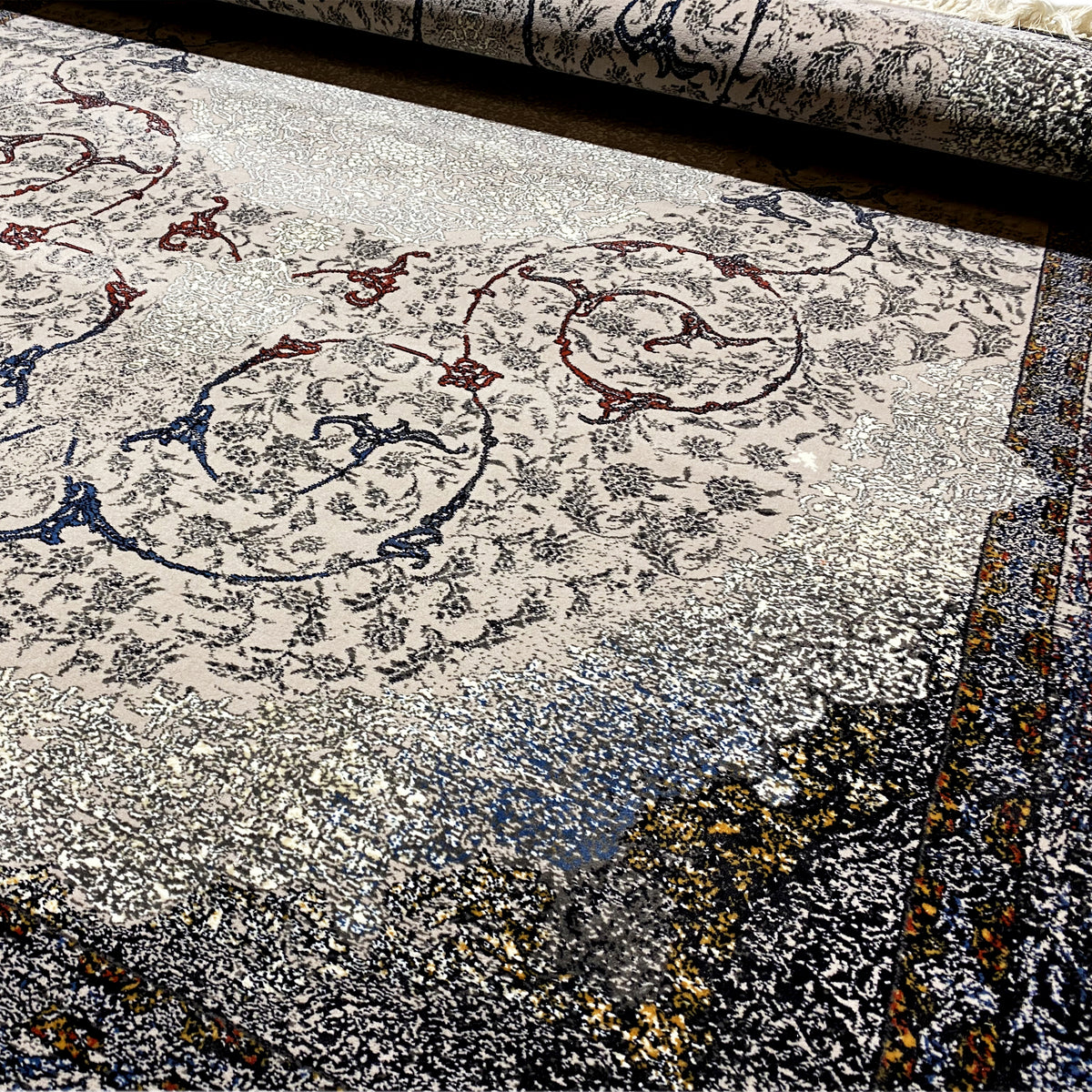 Teppichdetail mit Barockornamenten in Grau, Blau und Rot sowie strukturiertem, meliertem Flor