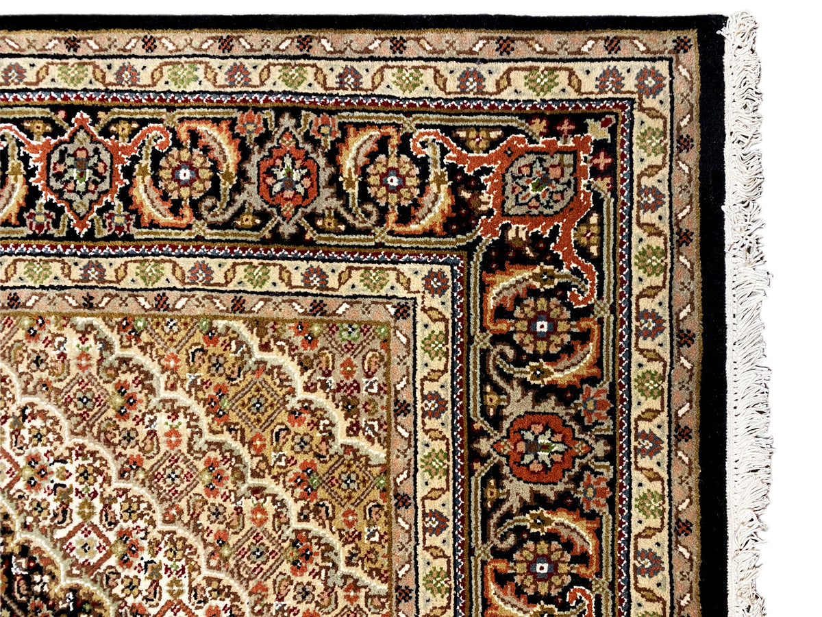 Nahaufnahme: Teppichbordüre mit bunten Ornamenten und dunklem Rand, Fransen am Saum.