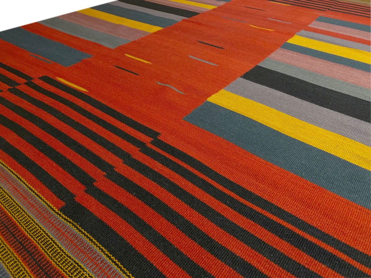 Kelim-Teppich Detail: orange-rote Fläche mit schmalen Streifen und bunten Rechtecken