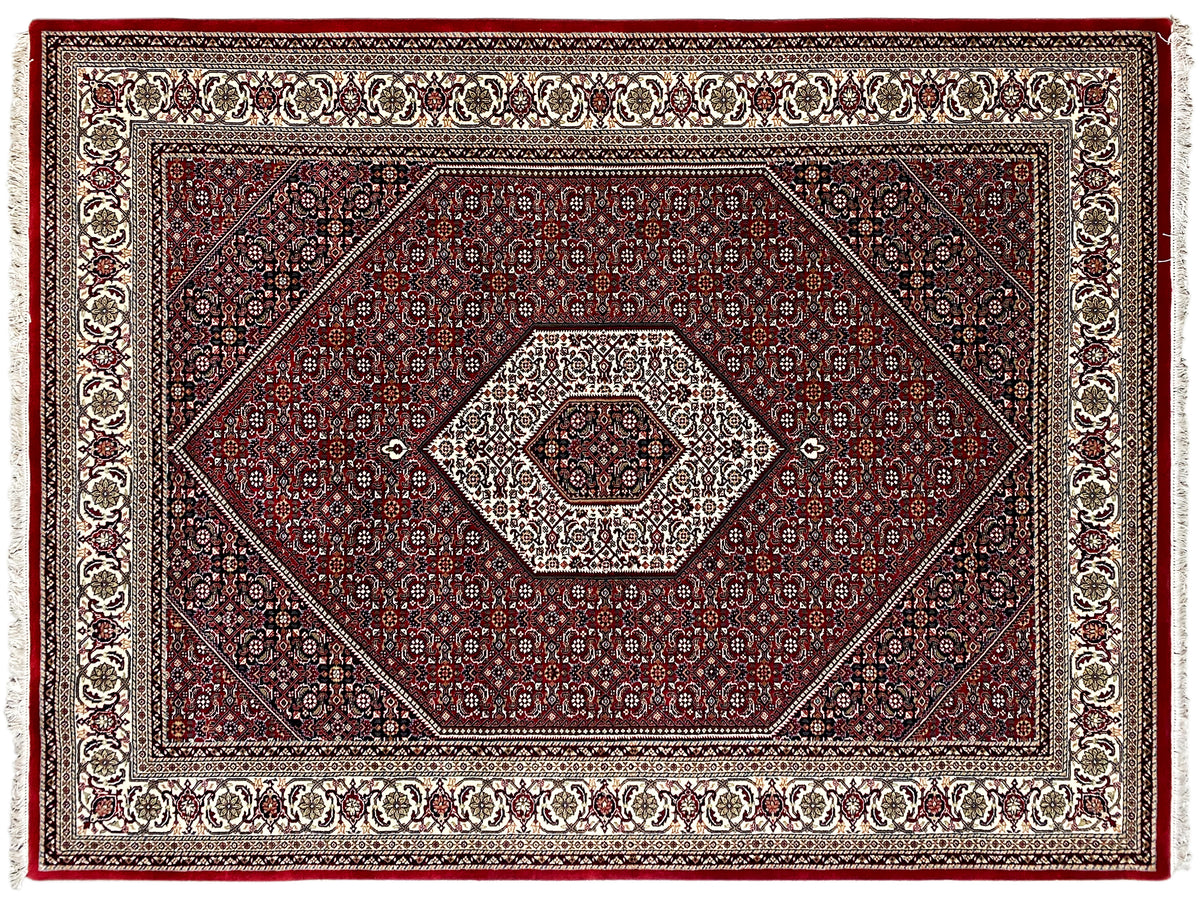 Nahansicht des roten Teppichs: Rauten- und Ornamentmuster mit Zierbordüre, Fransen